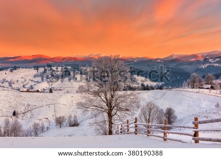 Fantastic winter mountain landscape with snow and fiery sky