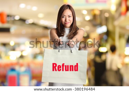 " REFUND " text on bag hold by smiling woman with blur shopping mall background Royalty-Free Stock Photo #380196484