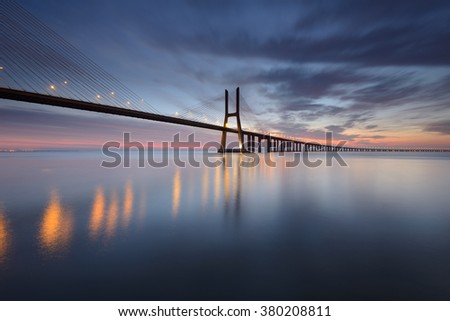 Lisbon and Vasco da Gama Bridge are an amazing tourist destination because their urban landscapes and its monuments. The Bridge crosses the Tagus River, and is one of the longest bridges in the world. Royalty-Free Stock Photo #380208811