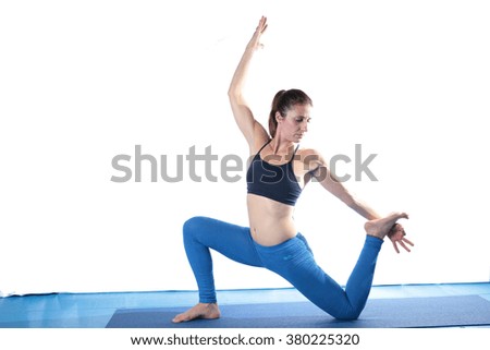 Woman practicing yoga on the floor on a blue mat and white background