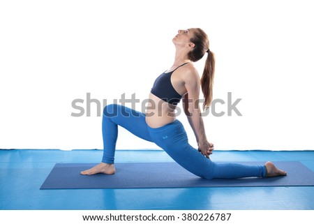 Woman practicing yoga on the floor on a blue mat and white background