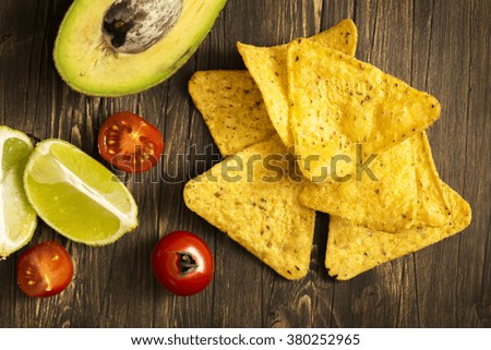 Corn tortilla chips Nachos and Guacamole sauce ingredients on wooden table. Top view