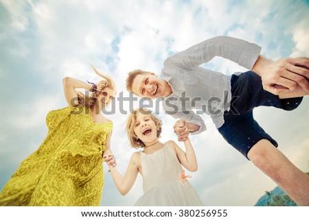 Laughing young family on the tropical sky background