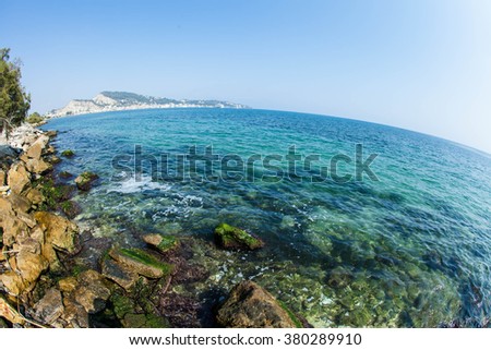 Greece. The island of Zakynthos. Seascape. Fisheye. Blue clear waters of the Ionian Sea. Stones lie on the beach. In the distance you can see the city