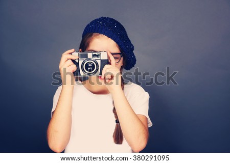 Young french girl taking a picture with a vintage film camera. Young fashion, photography, travel, foreign language learning and life style concept
