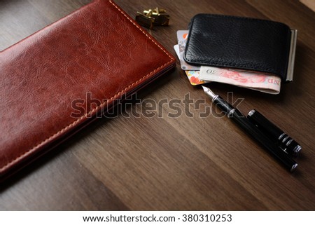 Business successful man accessories on the desktop in the office (diary, purse, money, sunglasses, credit cards, fountain pen)