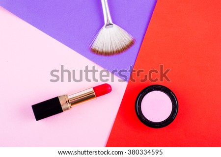 Lipstick, eye shadow and brush in bright fashion background. Pink, red and fuchsia makeup