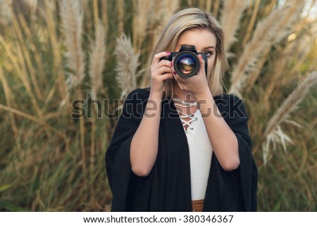 Young female photographer outdoors with digital camera and zoom lens