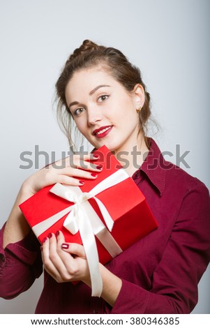 Beautiful girl gives or receives a gift, isolated on a gray background