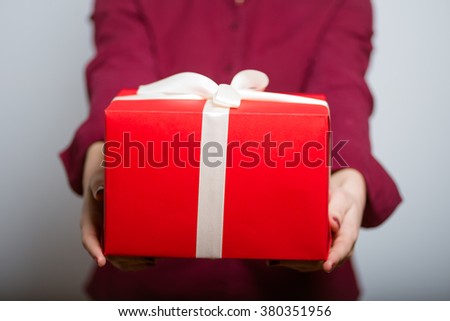 Beautiful girl gives or receives a gift, isolated on a gray background