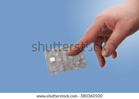 Male hand giving a grey credit  card with chip on gradient blue background