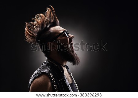 Profile shot of an angry punk rocker shouting on dark background Royalty-Free Stock Photo #380396293