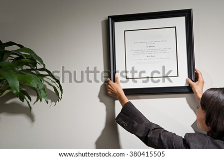 Business woman hanging framed certificate