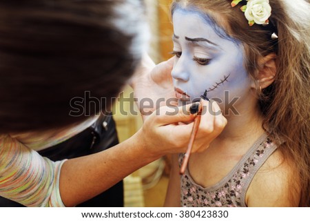 little cute child making facepaint on birthday party, zombie Apocalypse facepainting, halloween preparing Royalty-Free Stock Photo #380423830