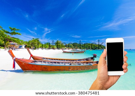Hand use smartphone buy tour online concept with tropical beach and sea background.