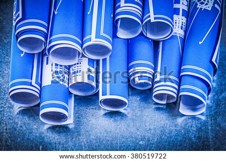 Blue rolled up construction plans on scratched metallic background maintenance concept.