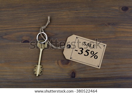 Key and a note on a wooden table with text - Sale 