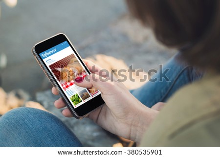 woman holding a smartphone and touching the screen with influencer website. All screen graphics are made up.