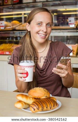 Young woman chatting mobile phone with a cake in cafe