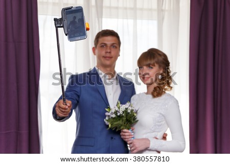 Bride and groom make selfie. Focus on phone.