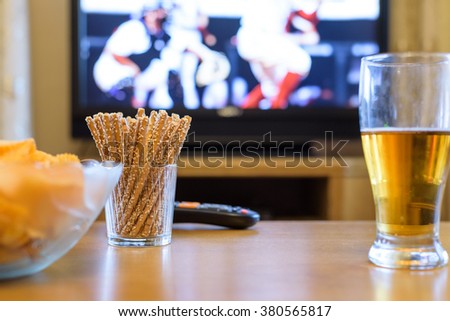 Television, TV watching (baseball match) with snacks and alcohol lying on table - stock photo