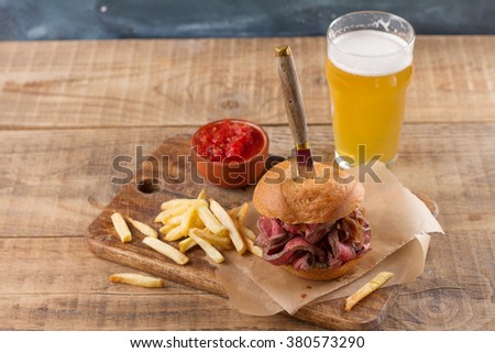 Tasty steak burger on a wooden board with potatoes and dipping sauce, selective focus