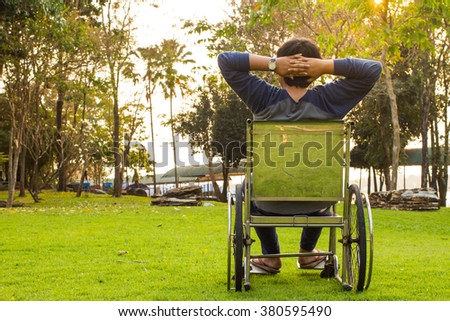 young man on wheelchair happy relaxing in a park with sunset
