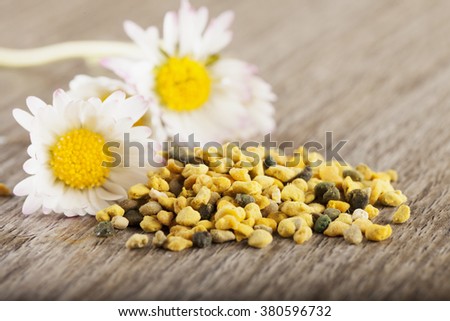 Pollen grains near a couple of white diasies, over table, horizontal image