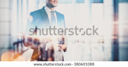 Photo of  businessman holding smartphone. Double exposure, city on the background. Blurred background