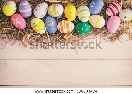 Colorful Easter Eggs in the nest of straw on the white wooden background 