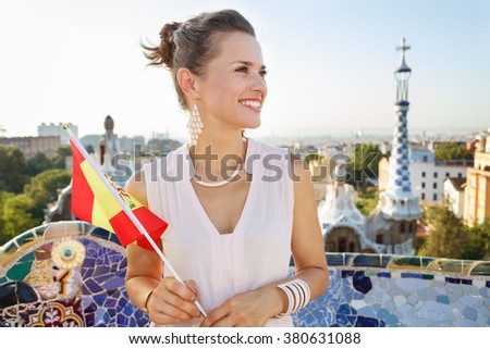Refreshing promenade in unique Park Guell style in Barcelona, Spain. Smiling young woman tourist with Spain flag in Park Guell, Barcelona, Spain looking into the distance
