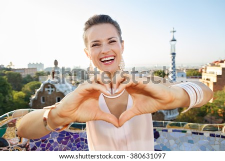Refreshing promenade in unique Park Guell style in Barcelona, Spain. Happy young woman tourist showing heart shaped hand in Park Guell, Barcelona, Spain