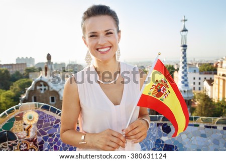 Refreshing promenade in unique Park Guell style in Barcelona, Spain. Portrait of smiling young woman tourist with Spain flag in Park Guell, Barcelona, Spain