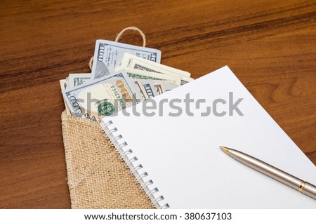 empty notebook with us dollar on wooden table