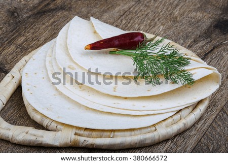 Fresh baked tortilla with dill branch on the wood background