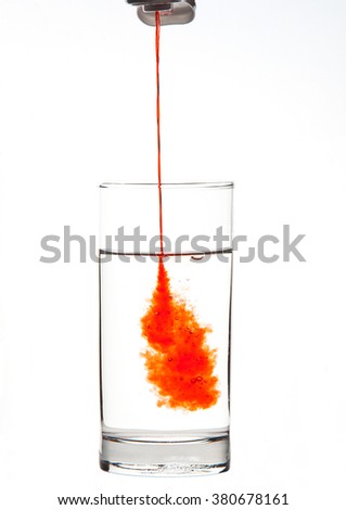 Adding Drink Enhancer to a Glass of Water isolated on a white background
