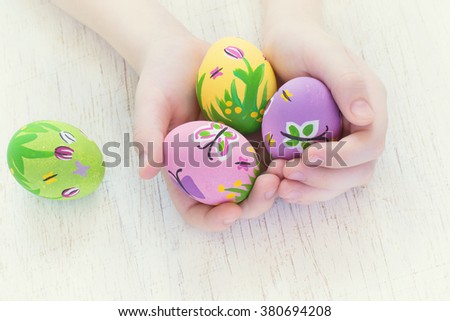 Painted Easter eggs with spring pictures in a child's hands
