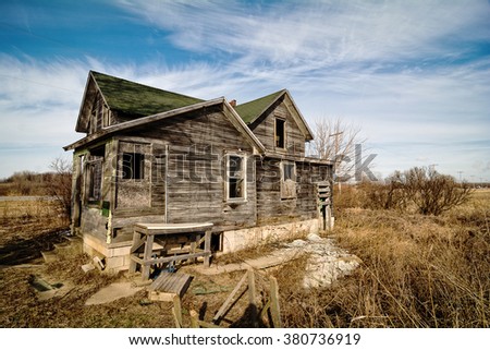 Photo of an old scary abandoned farm house that is deteriorating with time and neglect.