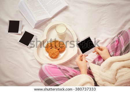 Woman in pajamas looking at photos on her bed