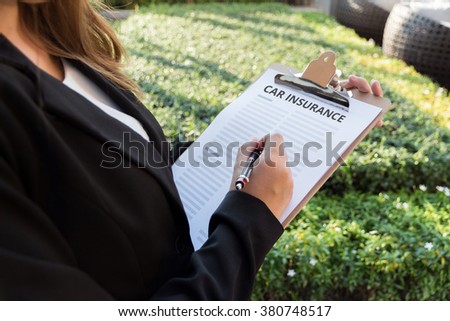 Businesswoman signing a car insurance policy on the street.