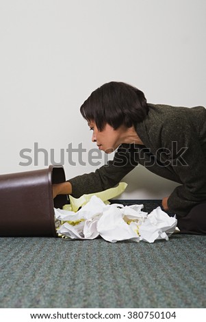 Businesswoman searching through rubbish bin