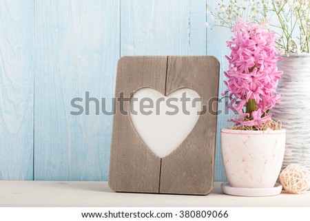 Heart shaped blank frame and spring flowers on blue wooden background