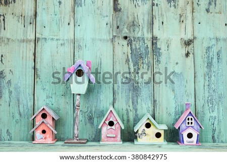 Row of colorful spring birdhouses by antique rustic mint green wood background