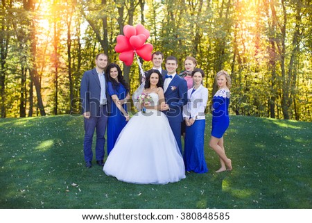 Newlyweds having fun with the guests in a meadow in the park