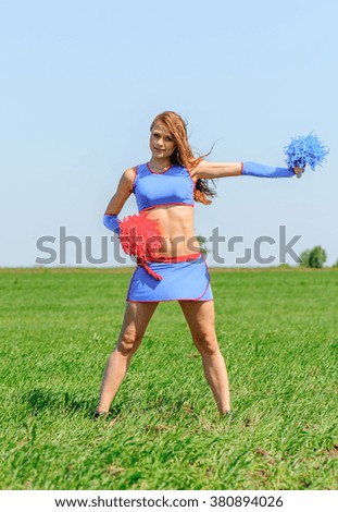 Young female cheerleader wearing blue suite on the grass