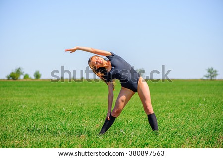 Young sportive girl show acrobatic tricks on the grass