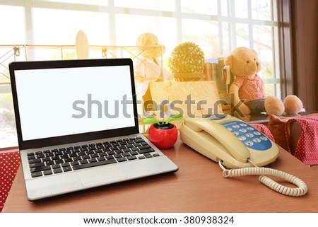 laptop and telephone with blur image of toy decoration in coffee shop background