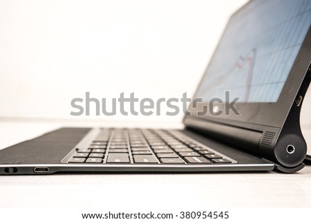 Black laptop with business charts on screen, on white table in office