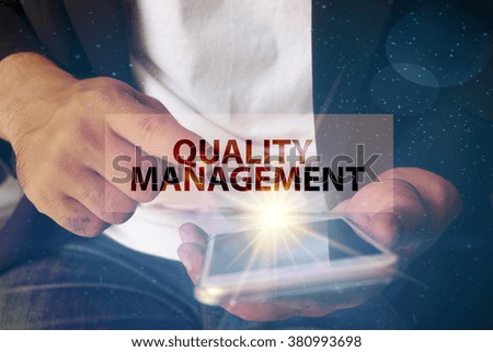 young man pointing at QUALITY MANAGEMENT  text on virtual screen. soft light with vintage filter. Internet concept. Business concept. Business idea