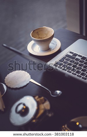 A cup of coffee and  laptop on a table.
